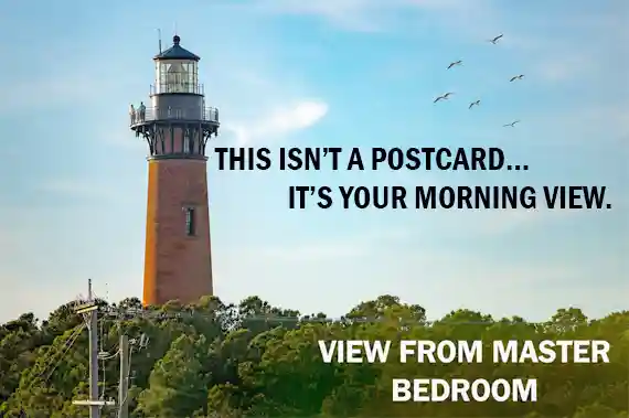Scenic view of Currituck Beach Lighthouse in Corolla Outer Banks with birds flying overhead and visitors on the observation deck, as seen from a nearby master bedroom window of Sonoma's Hideaway
